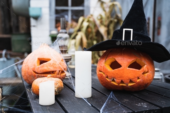 Orange pumpkin for halloween in black witch, wizard hat, jack-o-lantern with scary carved eyes,mouth