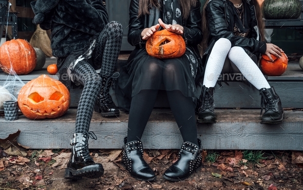 Scary girls,sisters,friends celebrating halloween.Treak or treat game.Pumpkins.Sitting porch steps