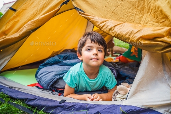 Small children, kids, boy play, sleep in sleepig bag in orange tourist tent. Family trip,hike to nat