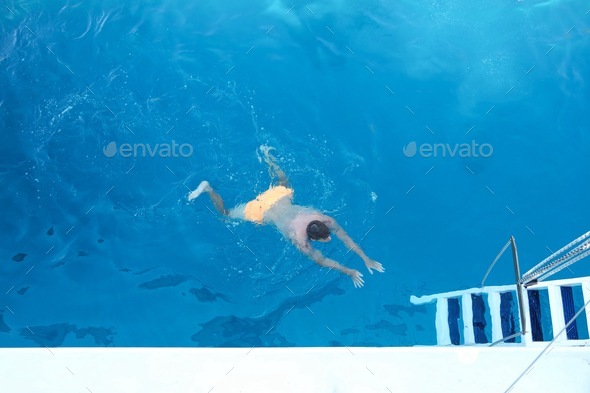 Man with the yellow swimming pants swimming in the beautiful blue Mediterranean Sea. View from above