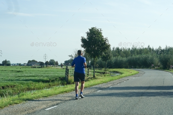 Elderly man running down the road in the country side.