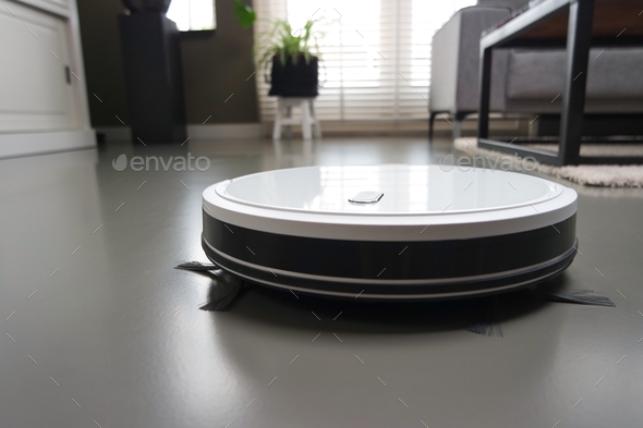 White robot vacuum cleaner cleaning floor in the living room.