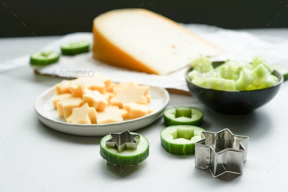 Making snacks from cucumber and cheese with the cookie cutter. - Stock Photo - Images