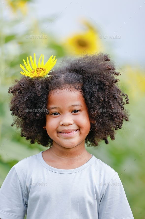 Little African American curly hair girl smiling with stick sunflower on ...