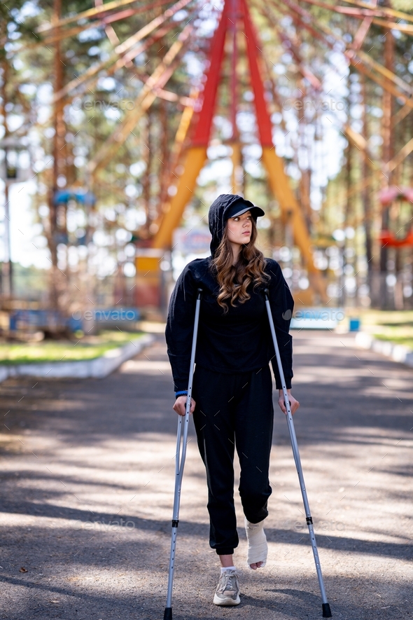 Woman in black clothes with crutches.