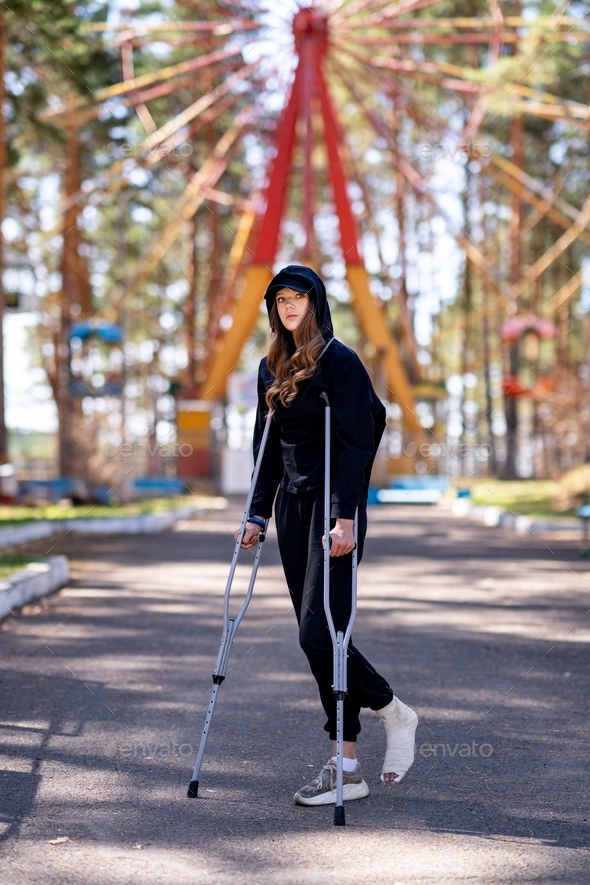 Woman in black clothes with crutches.
