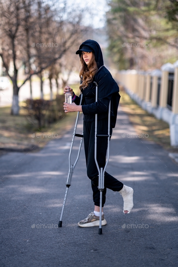  young woman with a broken ankle staying on road.