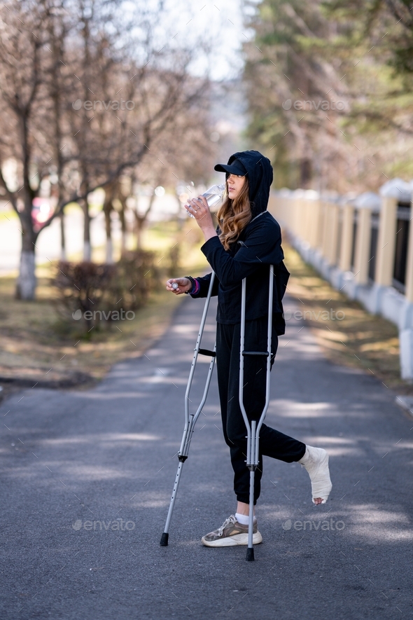  young woman with a broken ankle stays on road.