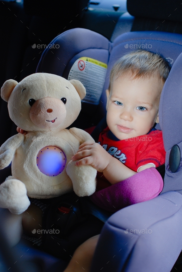 Little boy with teddy bear in car booster seat