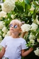 Beautiful little girl in stylish sunglasses in blooming flowers. - PhotoDune Item for Sale