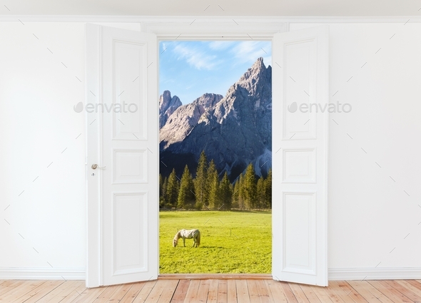 Wide open door in empty room with a view of mountains landscape and grazing horse outdoors