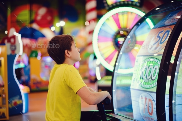 Preteen boy trying to win a jackpot at the slot machine in the amusement park.