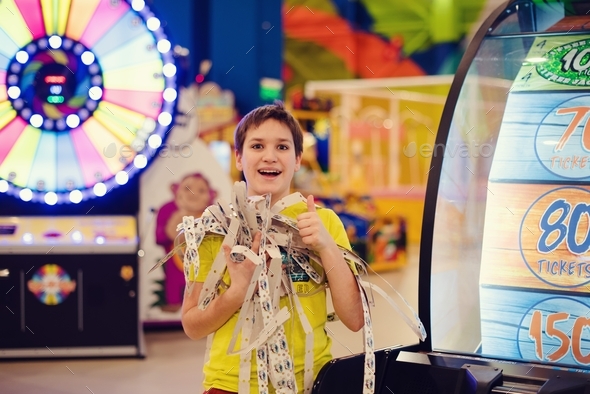 Excited preteen boy wins the jackpot at slot machine in the amusement park.