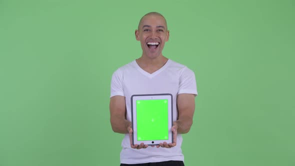Happy Handsome Bald Man Showing Digital Tablet and Looking Surprised alt
