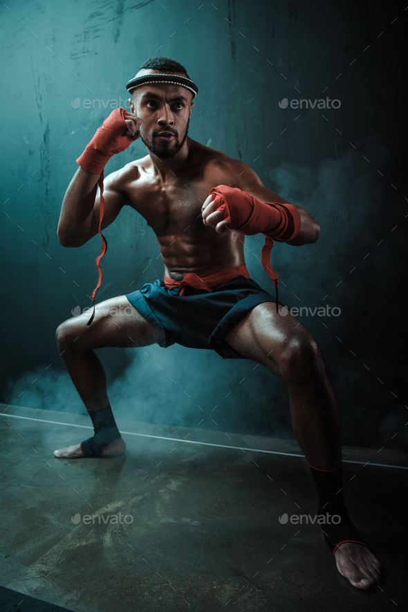 Determined Muay thai fighter training thai boxing and looking away, ultimate fight concept
