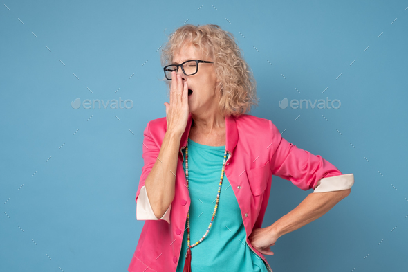 Senior woman yawning with hand in front of her mouth
