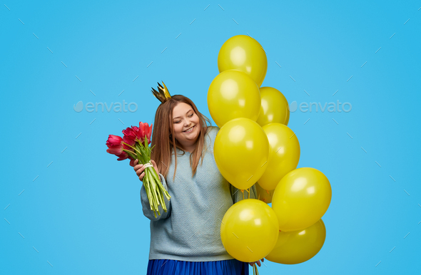 Cheerful plus size woman with flowers and balloons