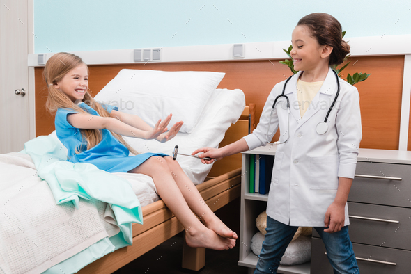 Happy kids playing doctor and patient with reflex hammer in hospital