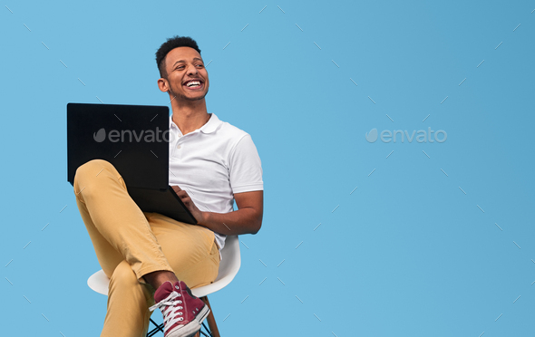 Cheerful black student with laptop looking away