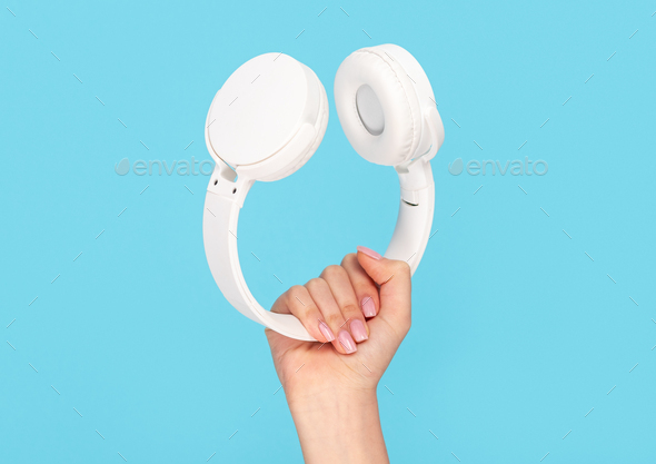 Female hand with stylish white headphones