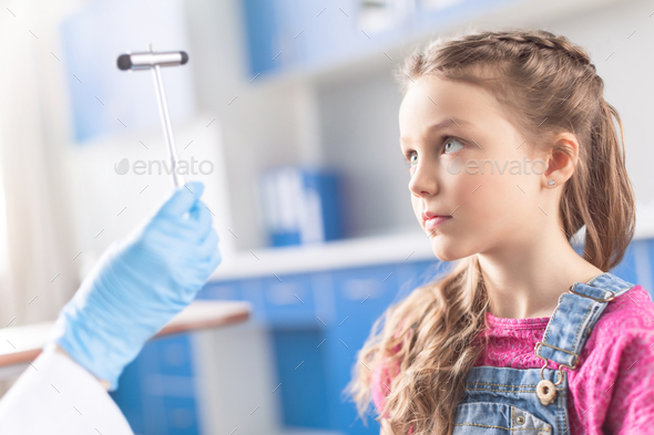 Cropped shot of doctor examining little girl with reflex hammer