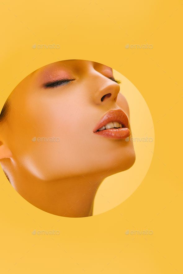 portrait of beautiful woman with shiny makeup in paper round hole with closed eyes isolated on