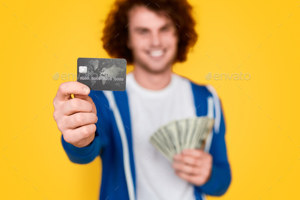 Blurred guy with money demonstrating credit card