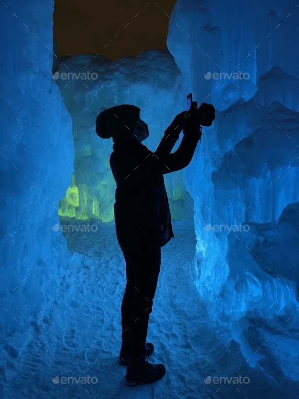 A man capturing photos of lights and ice in an ice castle.