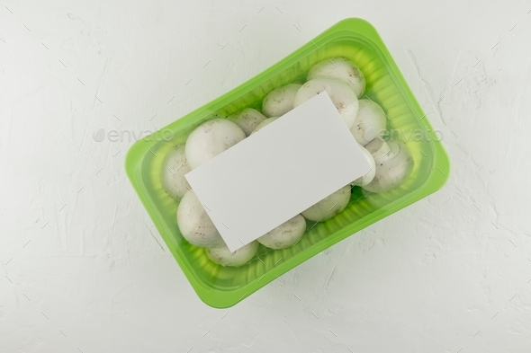 fresh mushrooms champignons in plastic vacuum packaging on a white background. top view. logo layout