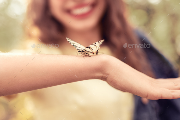 Butterfly sitting on arms of woman - Stock Photo - Images
