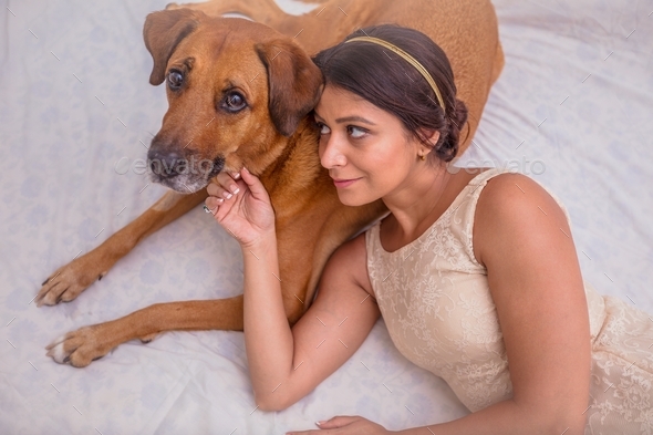 Beautiful young girl with her pet dog relaxing on the bed - Stock Photo - Images