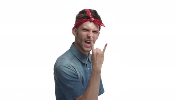 Sassy Cheerful Man with Beard Wearing Red Bandana Winning and Showing Rocknroll Gesture Shouting for