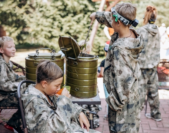 Group of teenager boys in camouflage relax and drinking tea after playing in laser tag shooting game