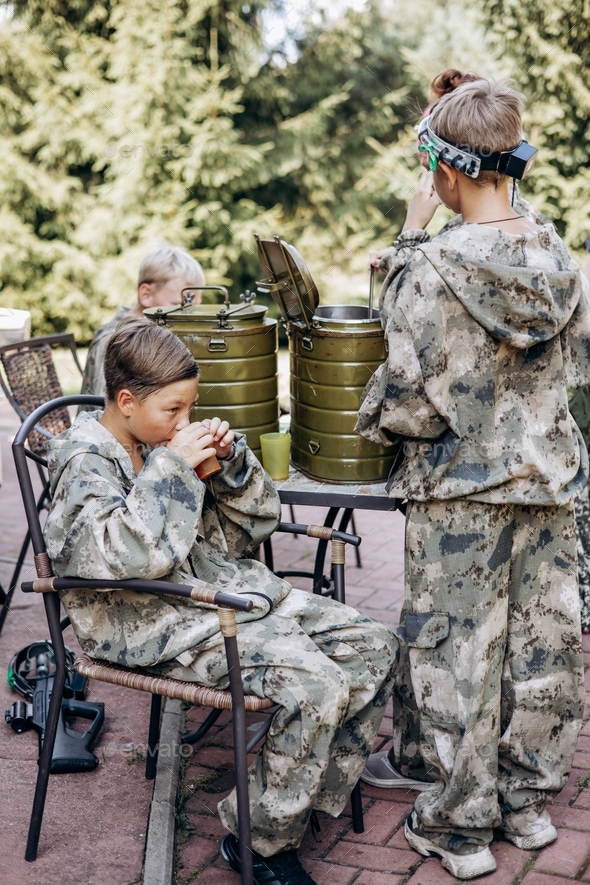 Group of teenager boys in camouflage relax and drinking tea after playing in laser tag shooting game