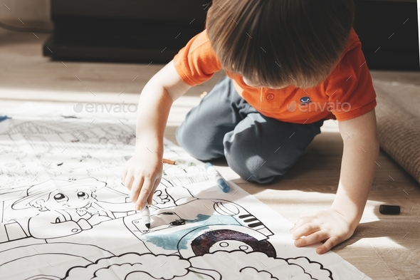  Cute little boy drawing with felt pens on floor at home. Early education concept.
