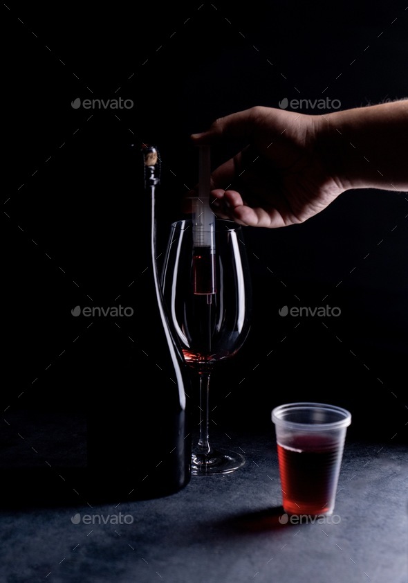 A man prepares wine in a glass for shooting by pouring wine through a syringe without splashing - Stock Photo - Images