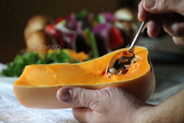 Man scooping seeds from butternut squash health and wellness Stock