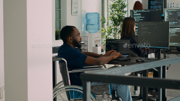 African american IT engineer with disability typing code in it development agency