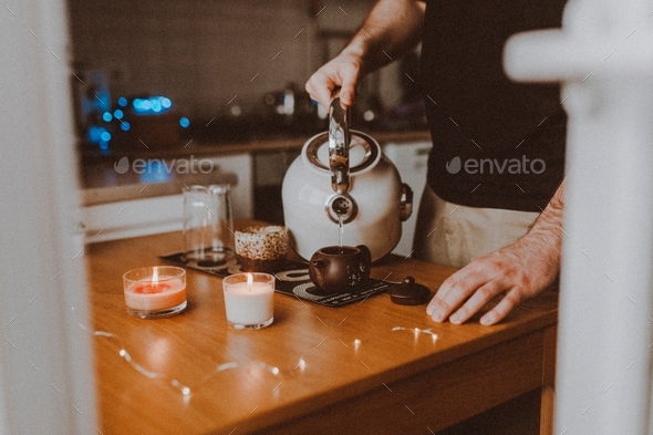 a young man makes tea and pours boiling water over Chinese tea puerh, candle lights