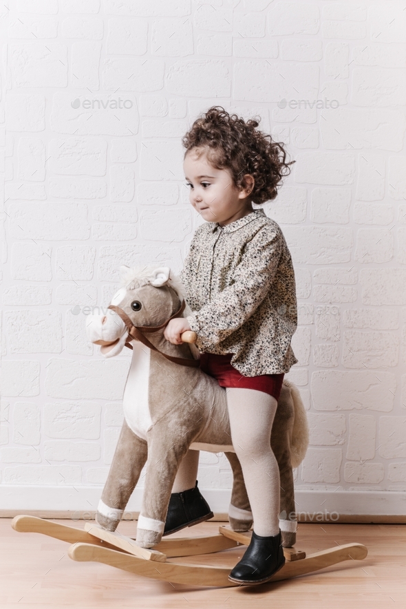 Little girl riding her wooden pony