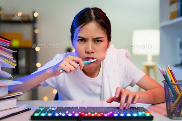 Busy Young Asian woman brushing teeth and hand typing on keyboard and hurry to work on time.
