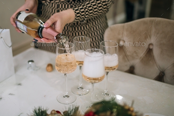 female hands pouring champagne into glasses, Christmas Eve party