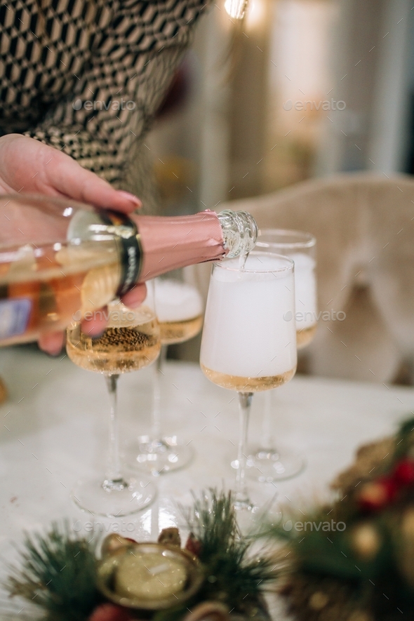 female hands pouring champagne into glasses, Christmas Eve party
