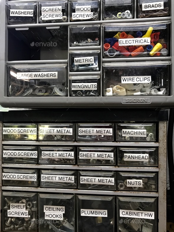 Close up of a two shelves with lots of labeled drawers for tools and things used in the garage