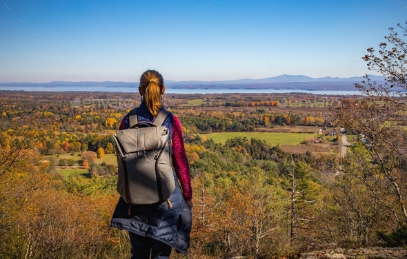 Woman on a hike looking out from atop a mountain at the beautiful fall countryside below