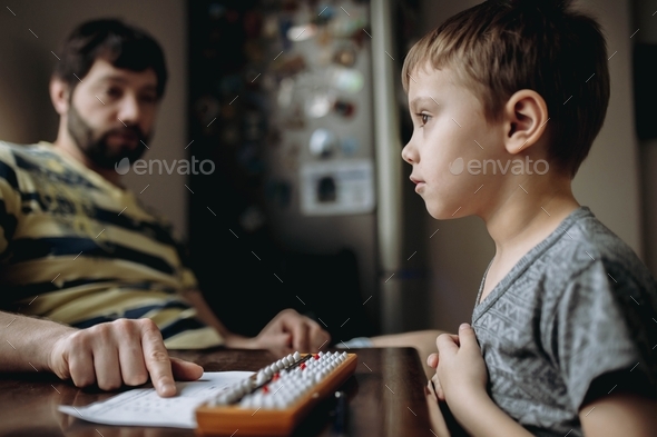 Little boy doing math homework, calculating with abacus (soroban) - Stock Photo - Images