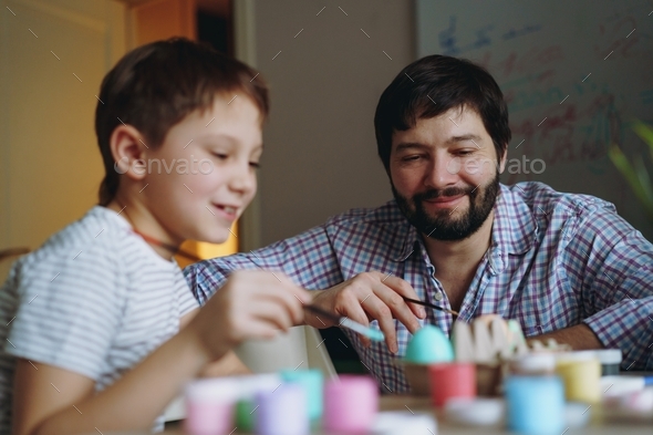 Father and son colouring eggs with acrylic paint