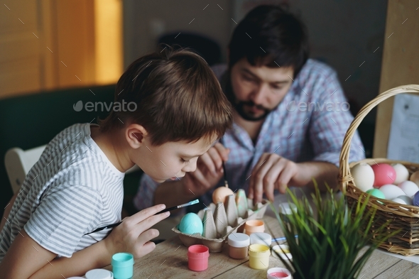 Father and son spending time together singing Easter eggs with gouache paint