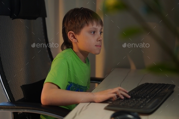 Cute caucasian boy playing video game at desktop computer at home - Stock Photo - Images