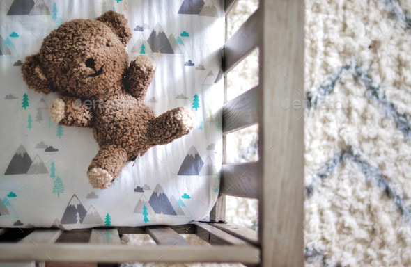 Brown teddy bear in a baby’s crib from above - Stock Photo - Images